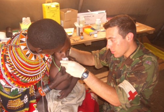 Alex Markus gives medical aid to childaid