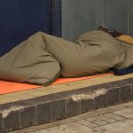 Homeless person in sleeping bag in doorway