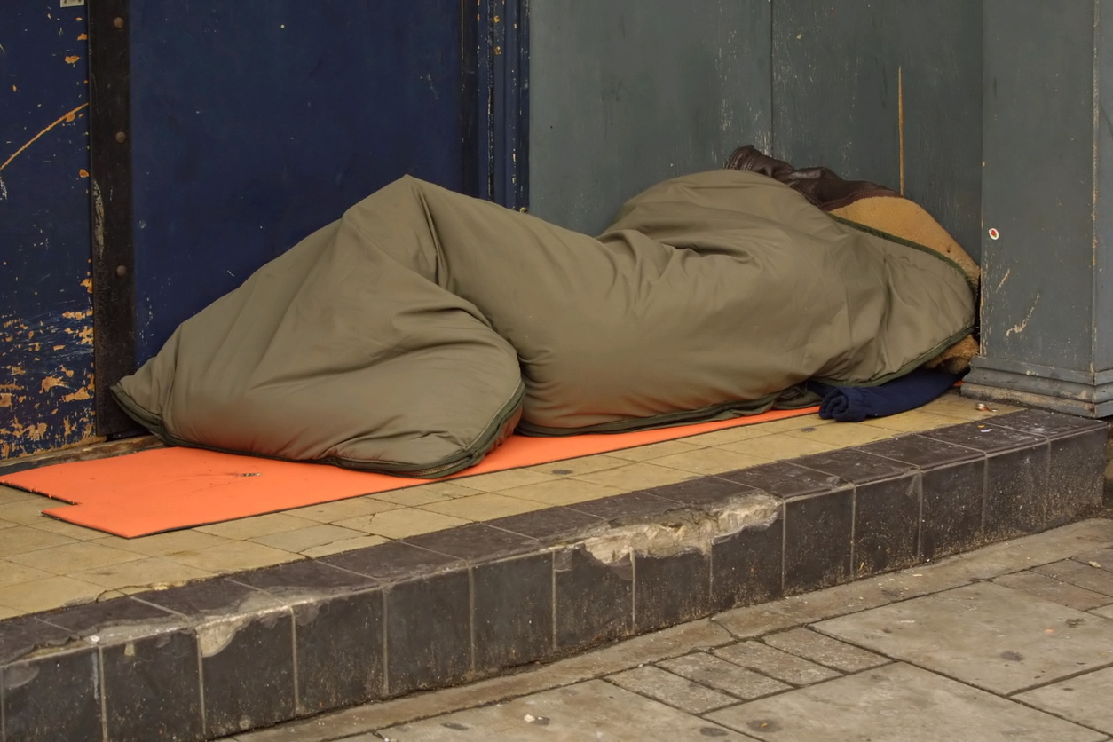 Homeless person in sleeping bag in doorway