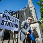 Old man with wlkaing stick leaving polling station
