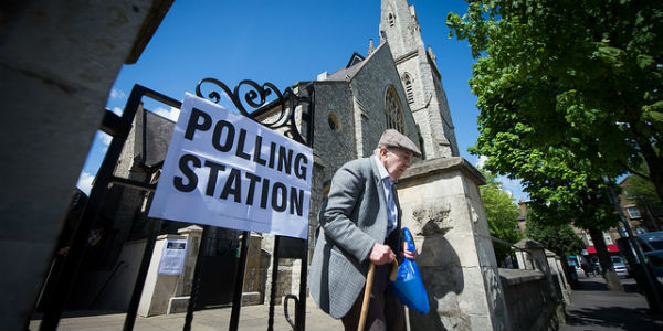 Old man with wlkaing stick leaving polling station