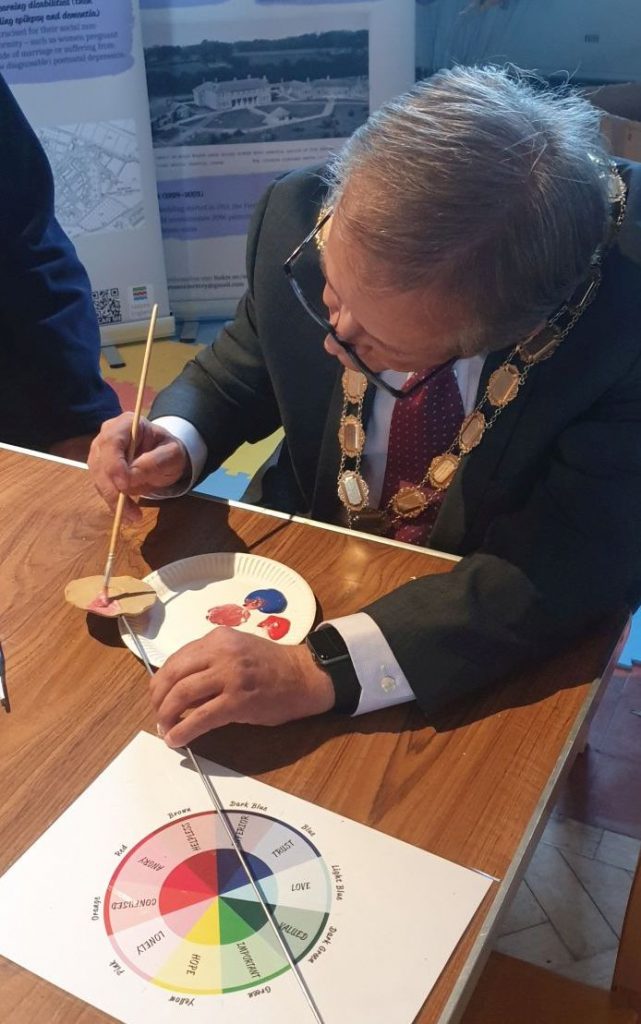 Mayor Clive Woodbridge painting a ceramic flower for Horton Cemetery