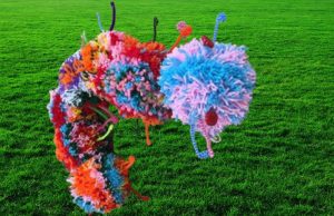 Caterpillar draft excluder made by partially sighted and blind members at Epsom from coloured wool pom-poms.