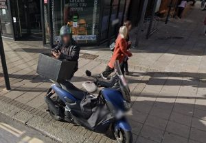 Delivery moped on pavement in Epsom
