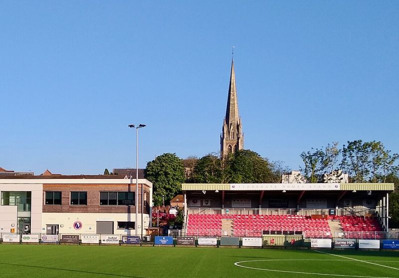 Meadowbank Stadium, the home ground of Dorking Wanderers Football Club, with the spire of St Martin's Church in the background (May 2021, looking south)