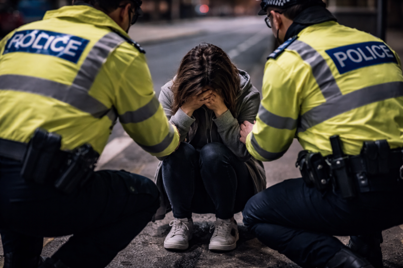 Depressed female in street approached by two police officers.