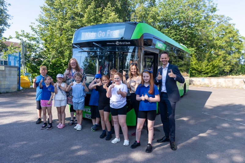 Children outside a bus with thumbs up